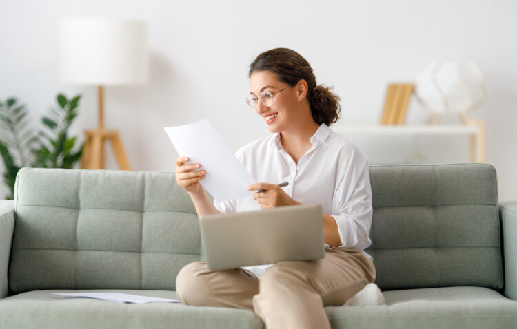 Happy woman studying online, watching webinar, podcast on laptop, making notes. E-learning concept.